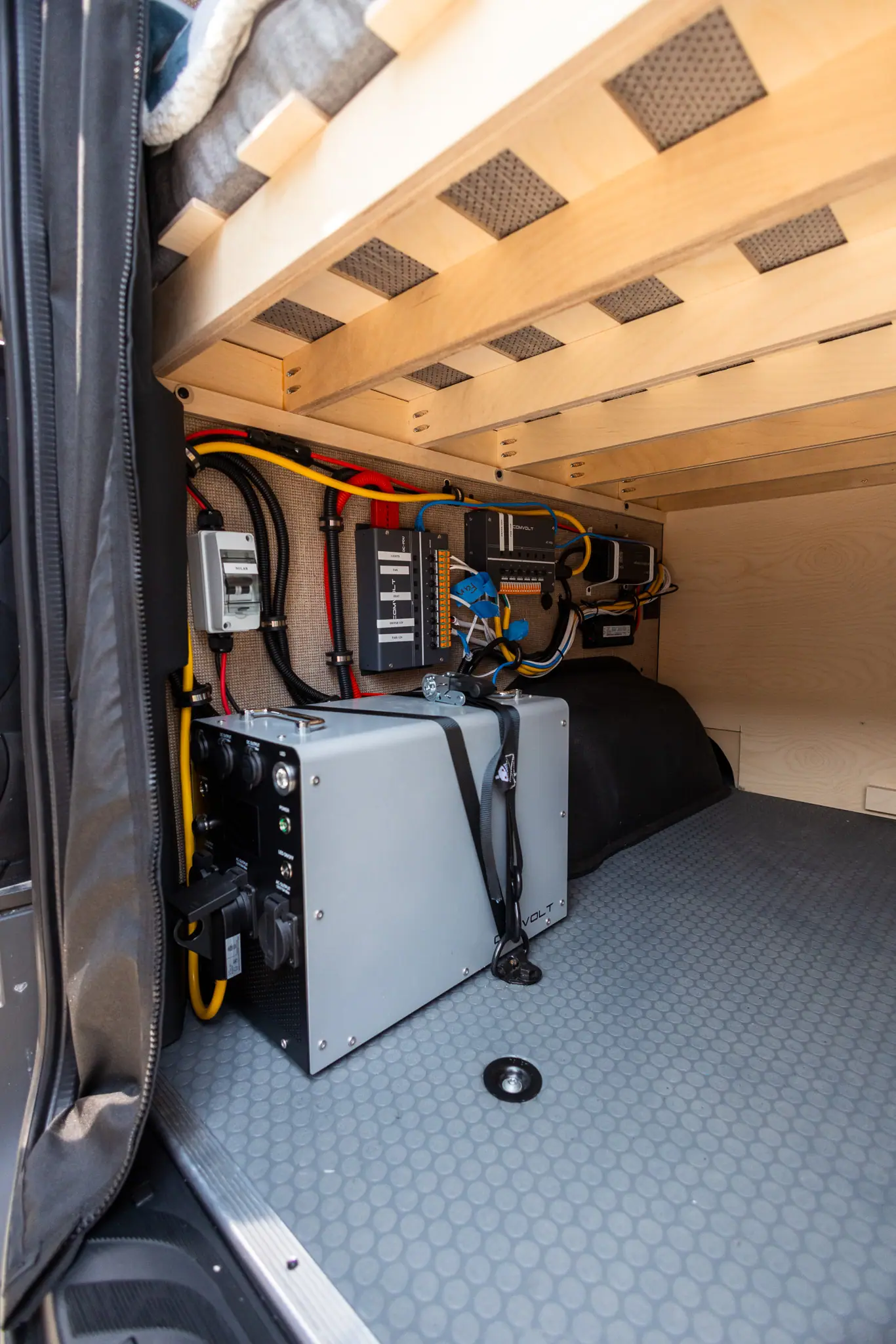 Camper van electrical system under the bed: power unit, solar breaker and a labeled 12V fuse panel