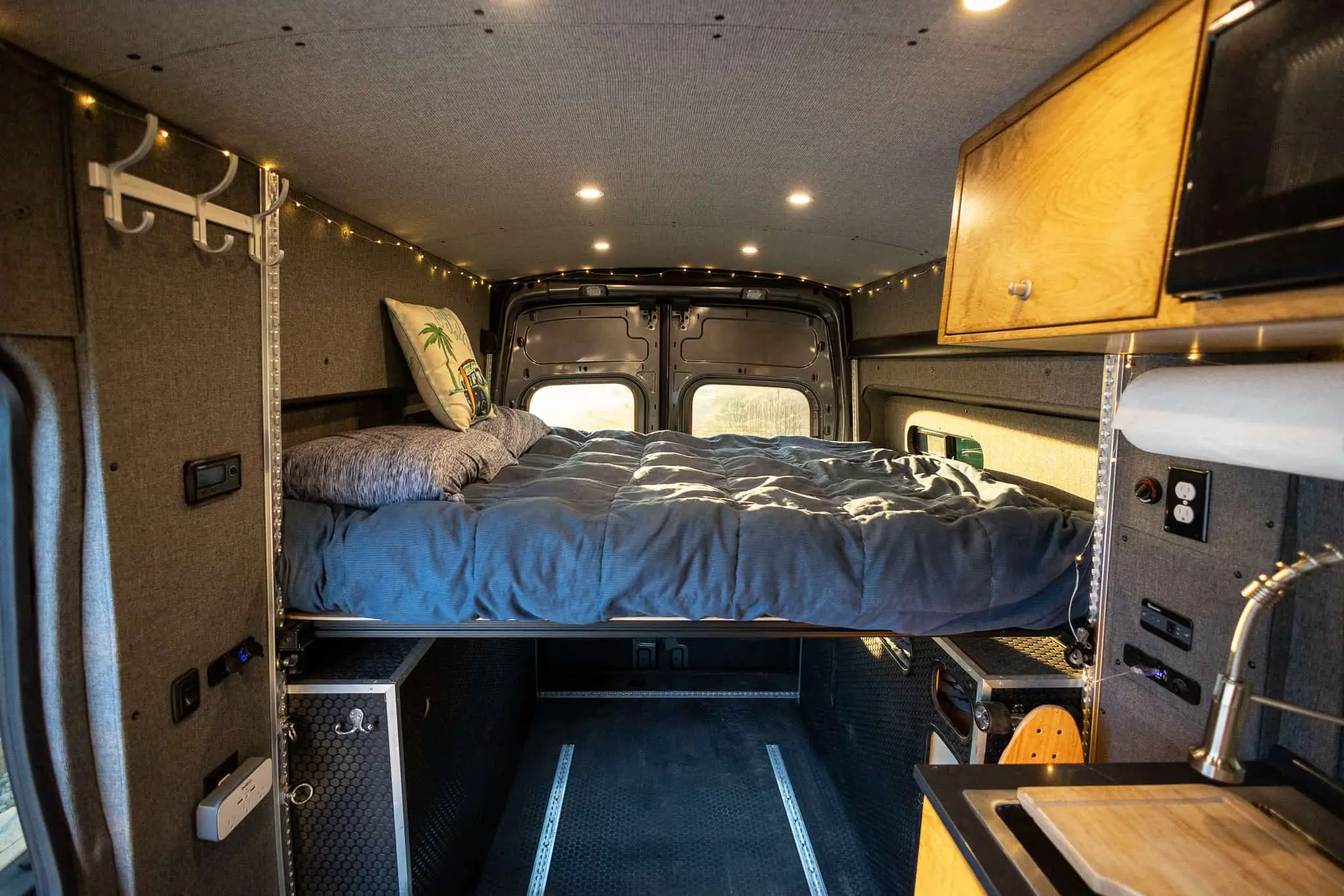 Rear platform bed over a gear storage garage in a Ford Transit camper van