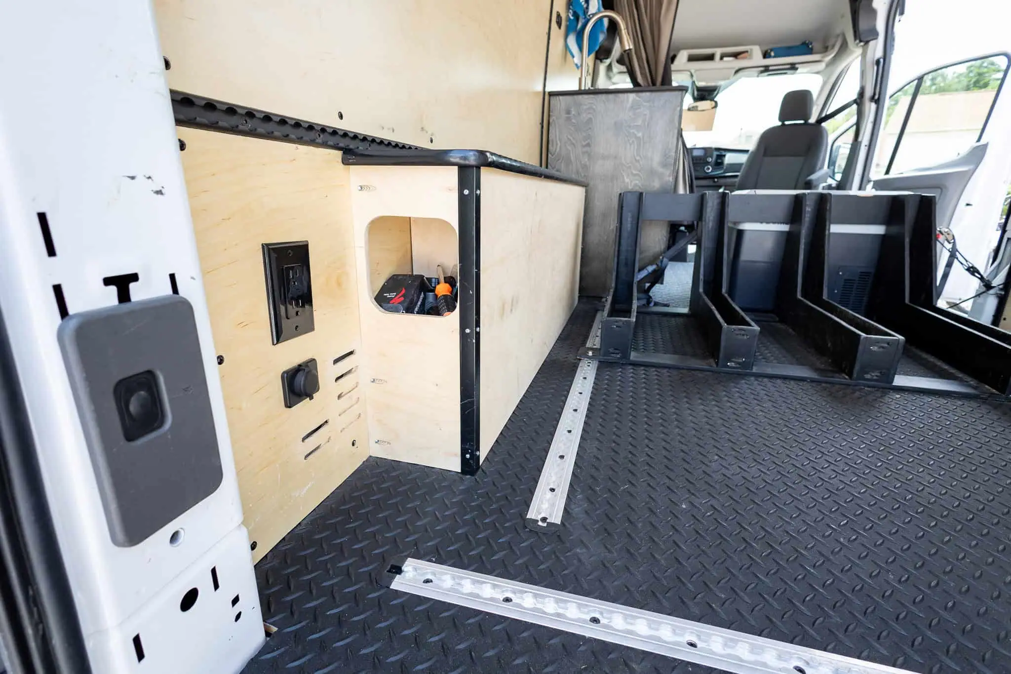 Van cargo area with L-track floor rails and a built-in box with 120V and 12V outlets