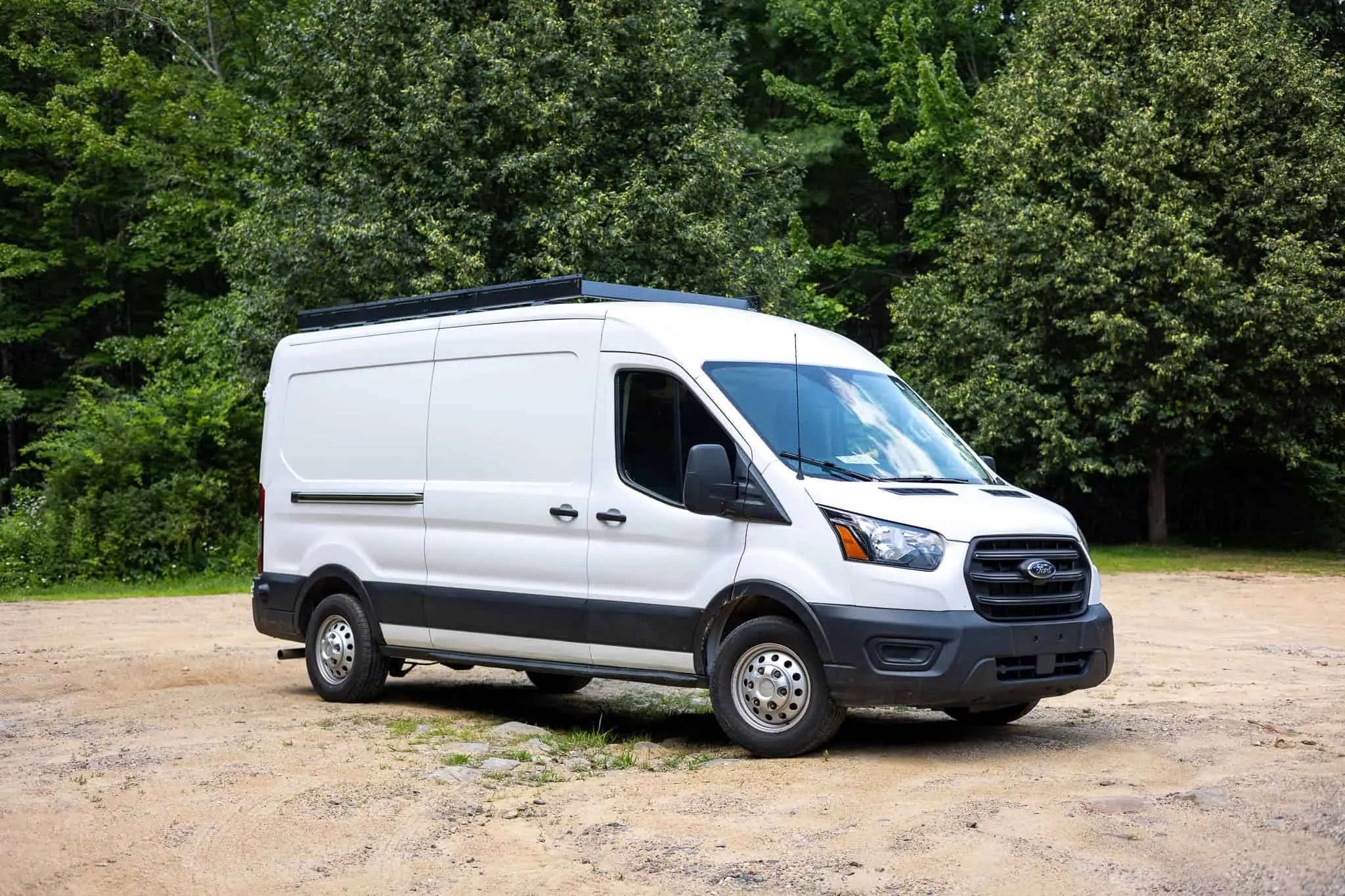 White Ford Transit mid-roof van with a black low-profile roof rack
